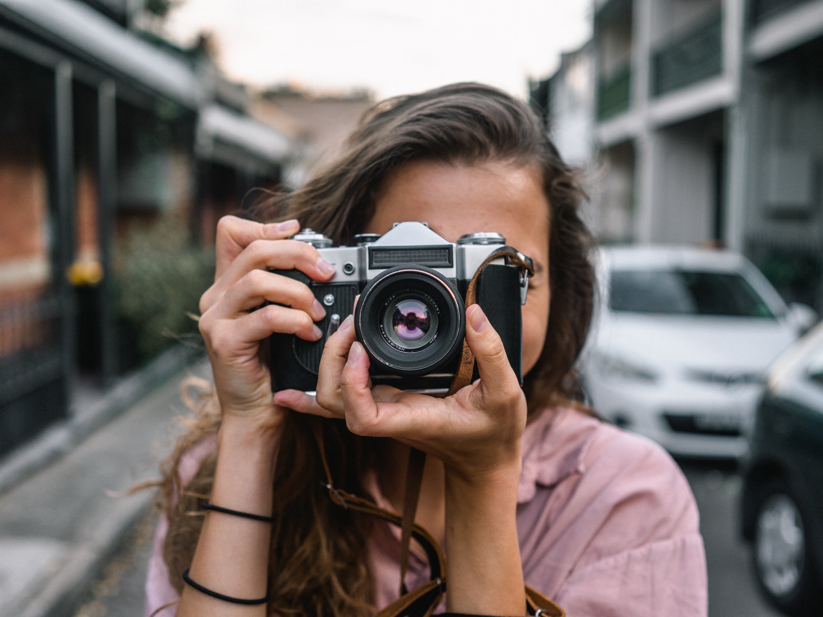 Photographer woman holding a camera pointing towards you