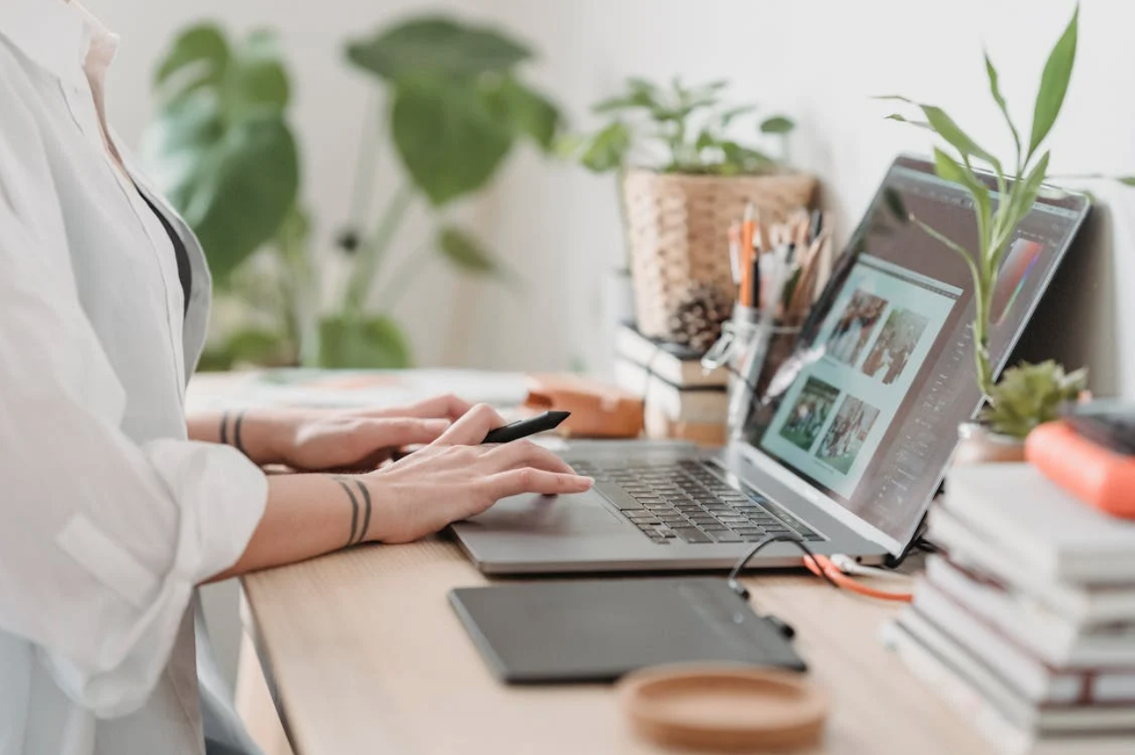 Someone at a desk looking at an online gallery on a laptop computer